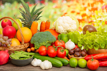 Group vegetables and Fruits Apples, grapes, oranges, pineapples, bananas in a wooden basket with carrots, tomatoes, guava, chili, eggplant, golden pod, green salad on wooden table in nature background
