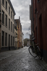 Fototapeta na wymiar Bike on the streets of Bruges. Bike with buildings and cloudy day. Old bike on the streets
