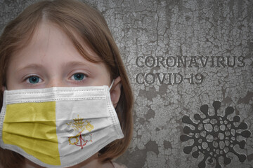 Little girl in medical mask with flag of vatican city stands near the old vintage wall with text coronavirus, covid, and virus picture. Stop virus concept
