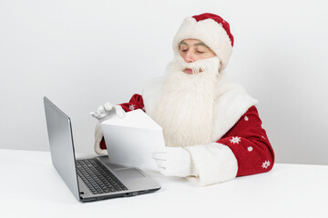 Santa Claus is sitting at his desk and reading letters.