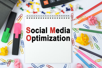 On the table is a calculator, diary, markers, pencils and a notebook with the inscription - Social Media Optimization