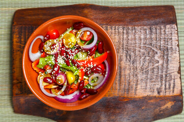 Clay Plate with Pan-Asian salad with sesame seeds on wooden stands.