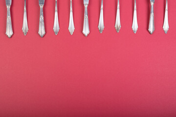 silver cutlery on a white tablecloth, forks, knives and spoons building a frame above