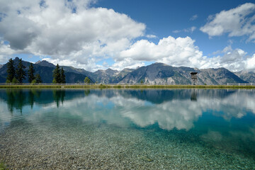 Klares Wasser eines Sees in Krahberg / Österreich mit weiter Gebirgskette im Hintergrund