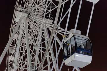 white Ferris wheel against the night sky, in the foreground a closed booth