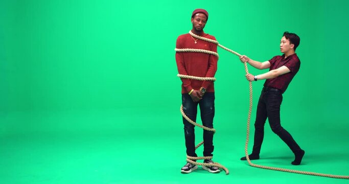 Studio, slow motion, green screen, two young men pose with a huge rope, London, UK