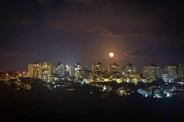 Moon over the night city. Ashkelon, Israel