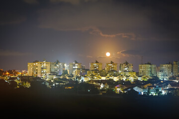 Moon over the night city. Ashkelon, Israel