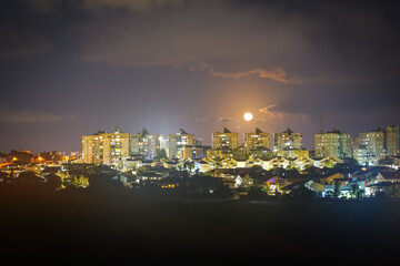 Moon over the night city. Ashkelon, Israel