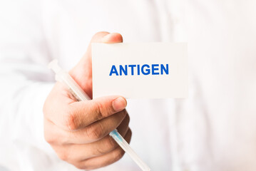 Word antigen on a white background with a syringe in hand. Medicine concept