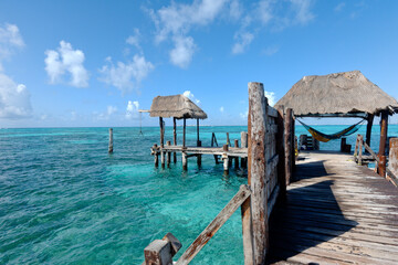 Rustic wooden pier on the sea. An unrecognizable young tourist rests on a hammock at the end of a wooden pier extended sun Caribbean sea in Isla Mujeres, Mexico