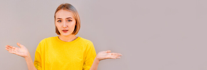 Studio shot of beautiful uncertain confused young female in casual clothes shrugging her shoulders,...
