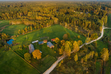 Soft colourful sunset light over the forest and countryside farm in distance.