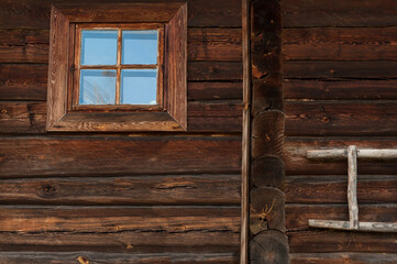 The wall of the house is made of old timber with a small window and a fragment of a staircase.