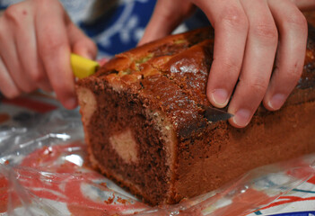 young woman in blue clothes cutting a portion of chocolate pudding into a blue plate