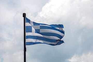 Flag of Greece on flagpole on clouds background