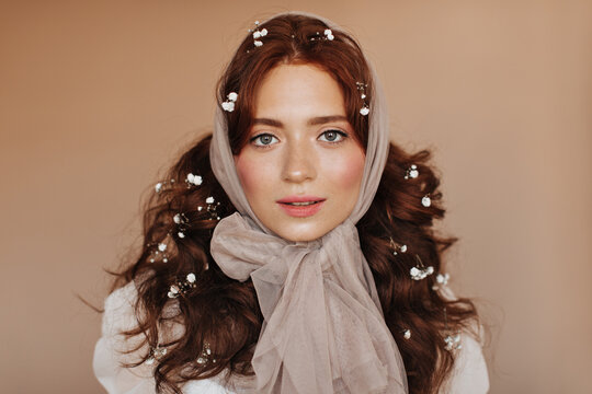 Sweet lady with freckles and bright blush posing on beige background. Woman in headcraft smiling