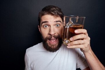 man with a mug of beer in a white t-shirt emotions lifestyle drunk on a dark isolated background