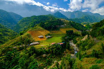 The indigenous Hmong village of Cat Cat in northern Vietnam with rice terraces of fertile soil in a lush valley with running water backed by a beautiful mountain range