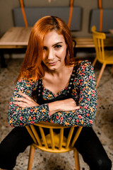 Redhead woman sitting in a yellow chair and staring to you