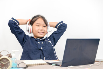 Cute and happy little girl children wear headphone and using laptop computer,