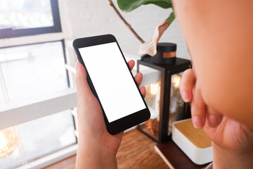 Mockup picture of business woman’s hands/man's hands holding smart phone with white blank screen in modern place.