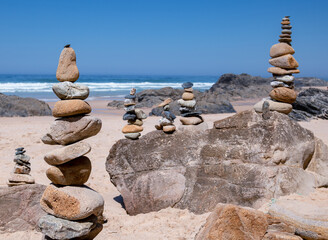 Group of towers from small stones balanced on the beach with the sea in the background
