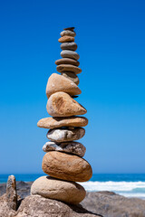 Fototapeta na wymiar Tower of small stones balanced on the beach with the sea in the background