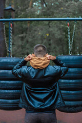 Obraz premium Young man pulling up, warming up on street workout area. Physical activity outdoors, caucasian man with tanned skin training, cloudy cold day, sport casual clothes
