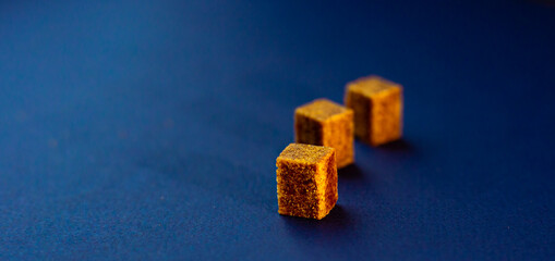 Brown sugar cubes on blue background. Diagrams concept.