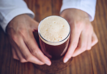 Someone holding a glass of Nitro cold brew coffee. Nitro coffee is unique type of coffee is cold-brewed and infused with nitrogen gas to improve both its taste and texture.