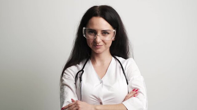 Female doctor in goggles and white coat posing at camera