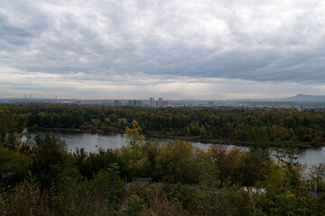 Panoramic view of the river with the city on the horizon, on a cloudy day.