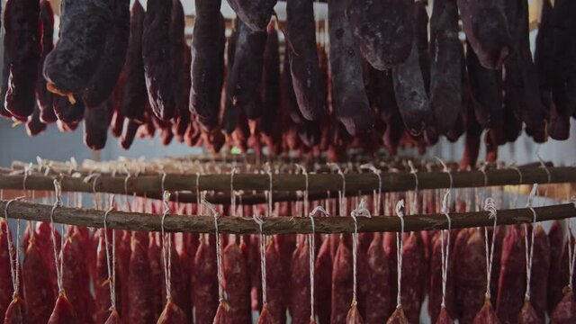 At meat factory in large smokehouse variety of salami and sausage sticks smoked and stored. Meat storage. Sausages production.
