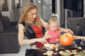 Family in a kitchen. People prepares to halloween. Family cuts pumpkins.