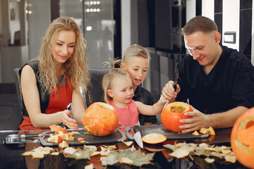 Family in a kitchen. People prepares to halloween. Family cuts pumpkins.