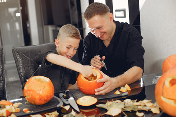 Family in a kitchen. People prepares to halloween. Family cuts pumpkins.