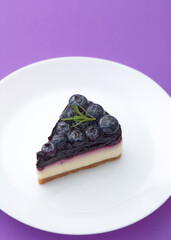 blueberry cheesecake  on white plate on violet background