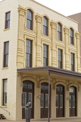 Fototapeta na wymiar Vertical: Historic stone building in Galveston Island, Texas with tall windows, brown doors, and awning