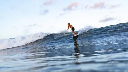 Young male athlete swimming on surfing board on the ocean. Bali, Indonesia. High quality photo