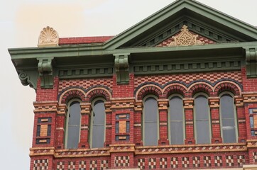 Fototapeta na wymiar Detail of historic building on Galveston Island, Texas with intricate, colorful brick designs, green roof, and facade