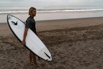 A surfer walking in from the water after a day out on the waves in Bali, Indonesia.Bali, Indonesia