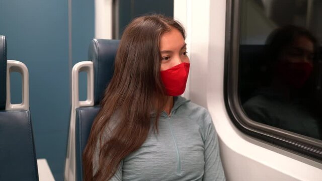 Woman wearing face mask in public transportation during coronavirus Covid-19 pandemic. Face mask concept with train transport commuter. Multiracial woman passenger using face mask on commute