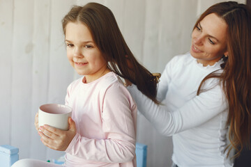 Beautiful woman with child. Woman in a white sweater. Little daughter in a room.