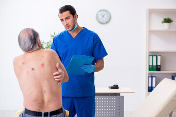 Obraz premium Old man visiting young male doctor dermatologist