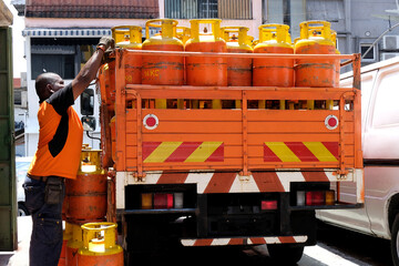 A man unloading canisters of cooking gas from a supply truck parked on a side street to deliver to...