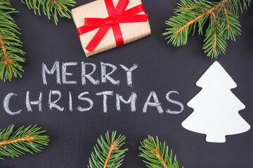 Inscription Merry Christmas, wrapped gift, christmas tree shape and spruce branches. Decoration for christmas time