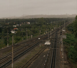 Obraz na płótnie Canvas Railroad tracks in cloudy weather against the background of a rainy city