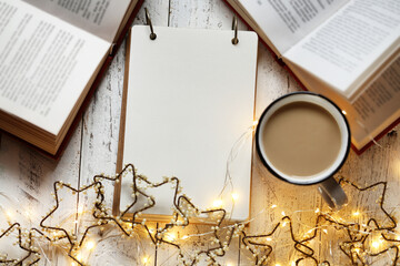 Christmas and New Year festive background.to do list on winter holidays. Shopping list, cup of tea and garland.Winter mockup. Plans for Christmas.Blank notepad and Winter books.Winter mood