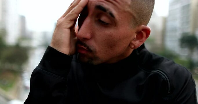 Troubled hispanic man thinking. Thoughtful worried guy in city